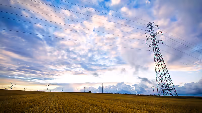 Pylône électrique haute tension et éoliennes au-dessus d'un champ, réseaux d'électricité
