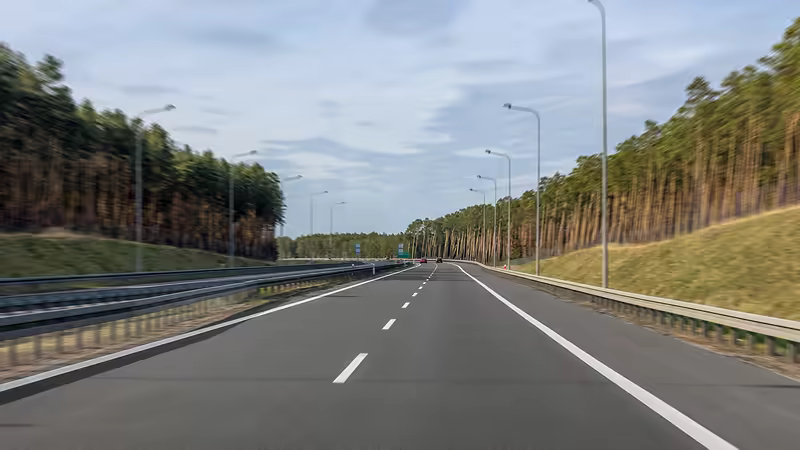Autoroute à deux voies bordée de glissières et de lampadaires, projet de voirie