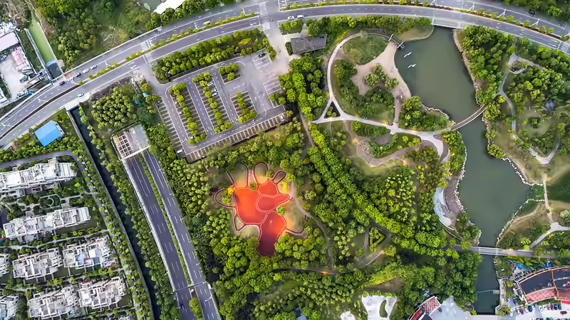 Vue aérienne d'un aménagement avec routes, parking, espaces verts et plan d'eau, travaux de VRD